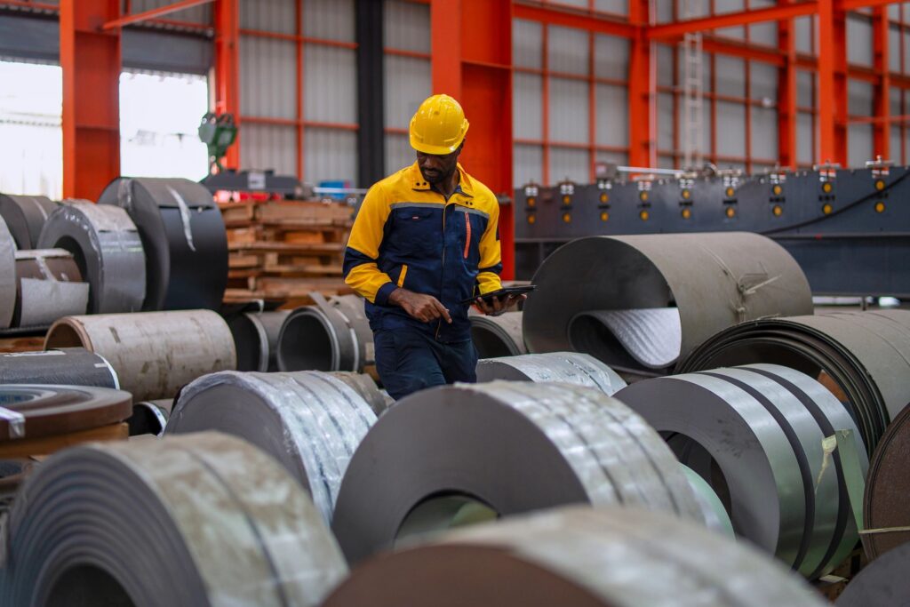 The blue collar worker is working at the metal sheet factory.